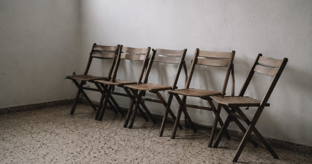 Una fila de sillas plegables contra la pared de una sala vacía