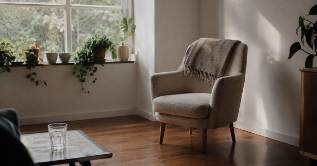 Habitación luminosa con un sillón junto a la ventana y plantas en el alféizar