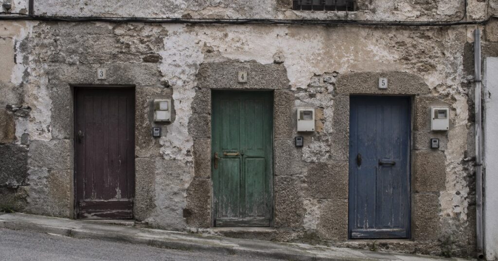 Fachada de una casa de pueblo dividida en tres viviendas, con tres puertas distintas