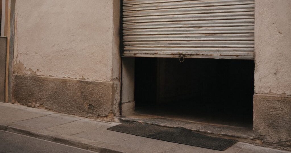 La persiana de un local comercial a media altura, vista desde la calle