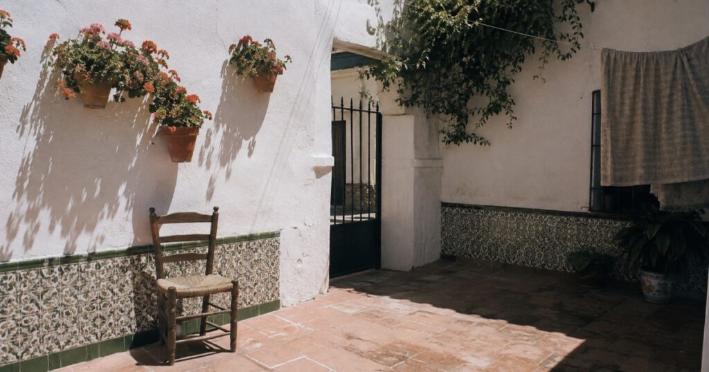 Patio andaluz de una casa familiar con paredes encaladas y macetas de geranios