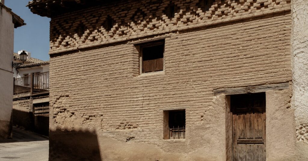 Fachada de ladrillo de una casa aragonesa con una franja de labor mudéjar bajo el alero