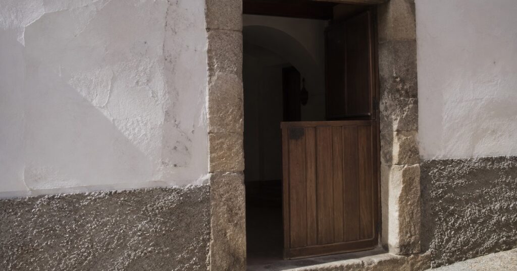 Zaguán de una casa extremeña con la puerta partida y la mitad de arriba abierta