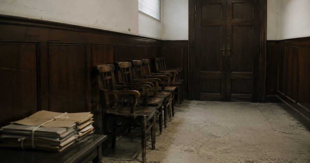 Sala de espera vacía de una notaría con sillas de madera y carpetas atadas